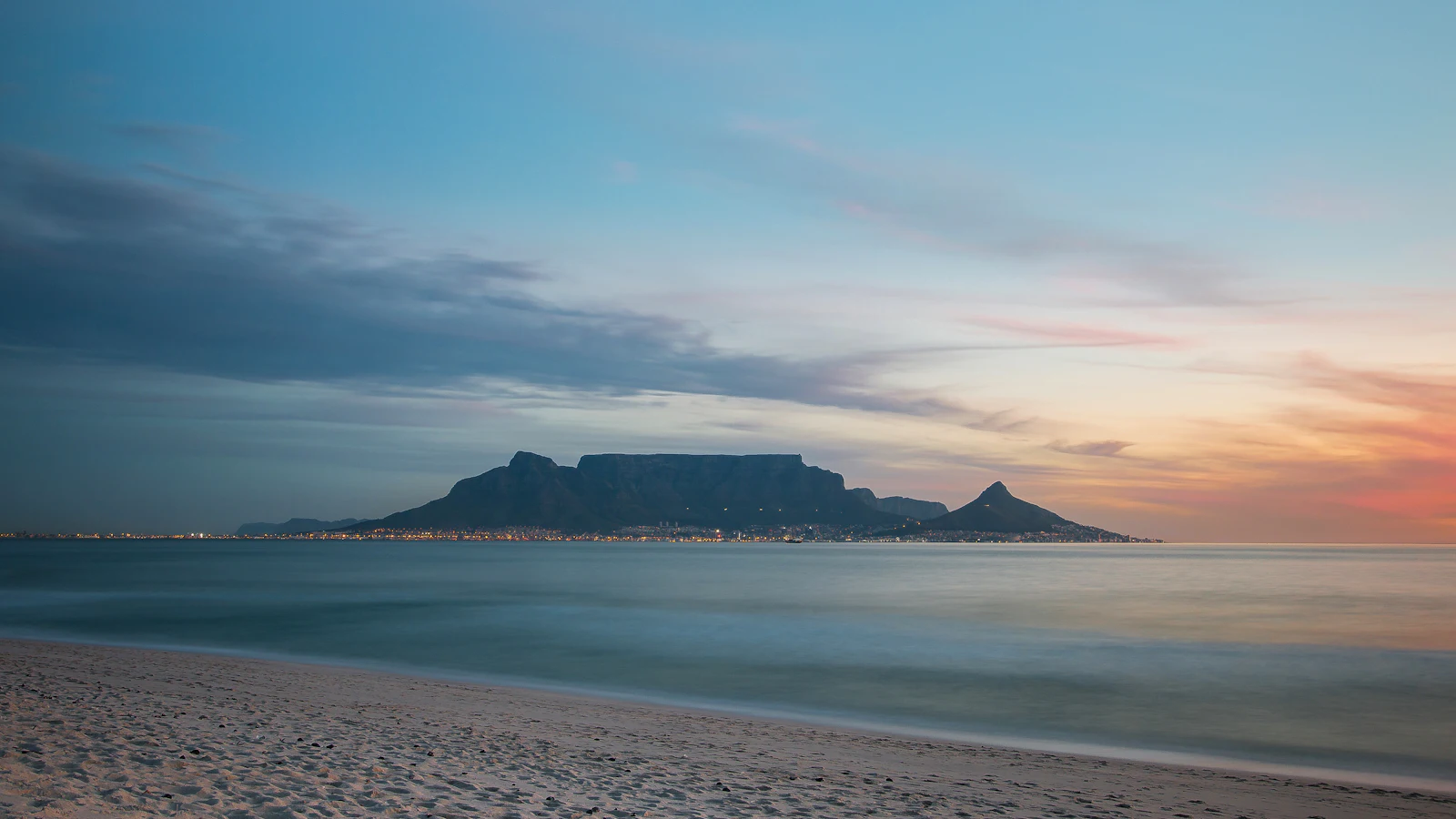 Table Mountain and Lion’s Head across Table Bay at dusk, seen from the beach, in black and white